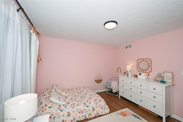 bedroom with dark hardwood / wood-style floors and a textured ceiling