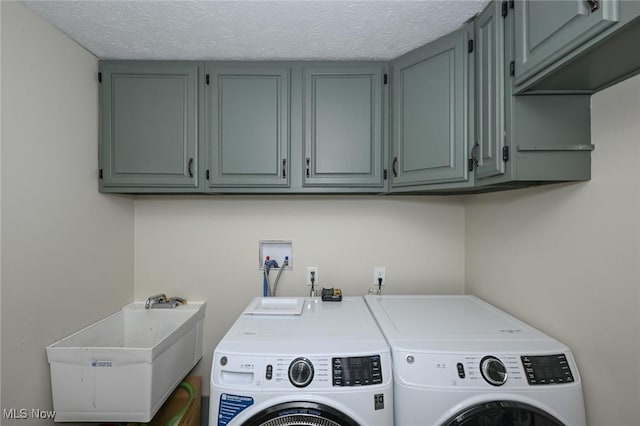 washroom with sink, washing machine and dryer, cabinets, and a textured ceiling