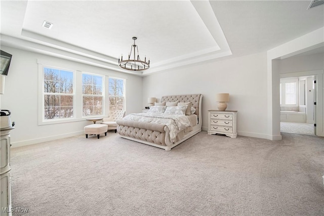 carpeted bedroom featuring an inviting chandelier and a tray ceiling