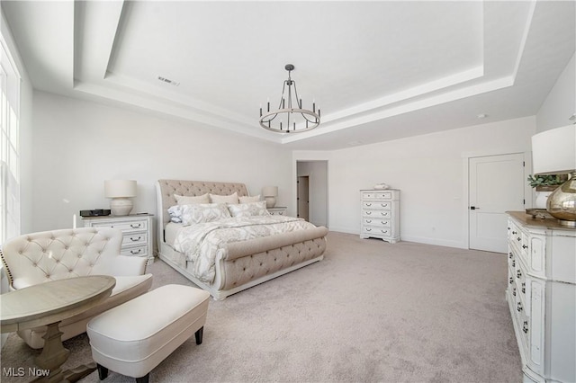 carpeted bedroom with an inviting chandelier and a tray ceiling