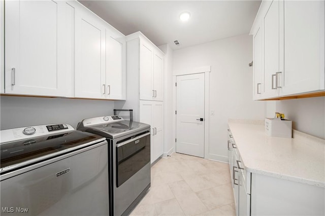 washroom featuring cabinets, washer and dryer, and light tile patterned floors