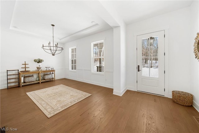 entrance foyer with dark hardwood / wood-style flooring, a notable chandelier, and a tray ceiling