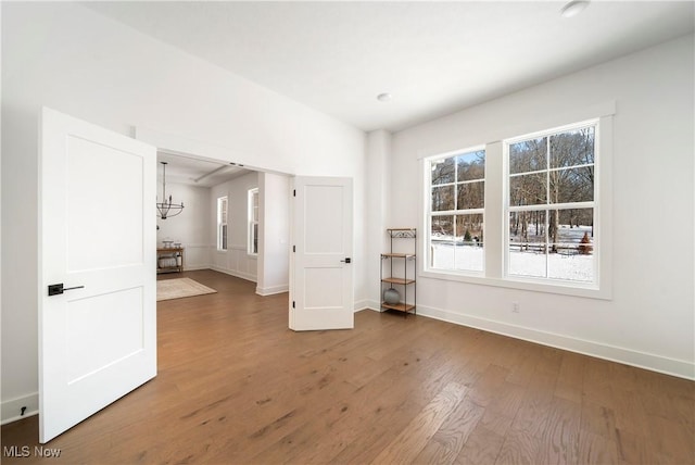 unfurnished room with an inviting chandelier and dark wood-type flooring