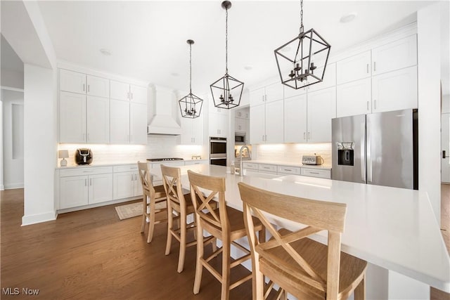 kitchen with pendant lighting, stainless steel appliances, a large island, and white cabinets