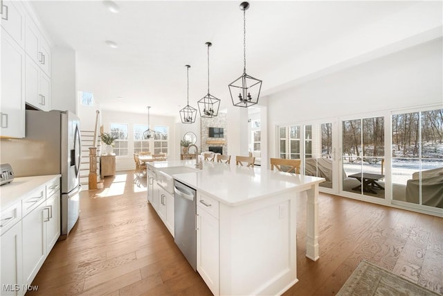 kitchen featuring a kitchen bar, sink, an island with sink, stainless steel appliances, and a fireplace