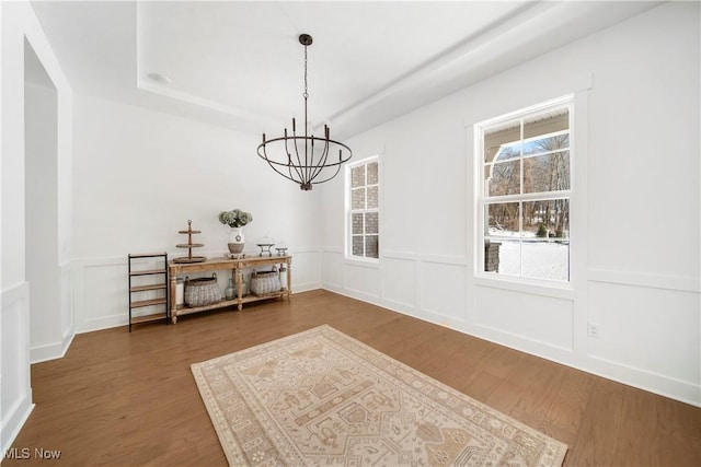 unfurnished dining area featuring a tray ceiling, dark hardwood / wood-style floors, and a notable chandelier