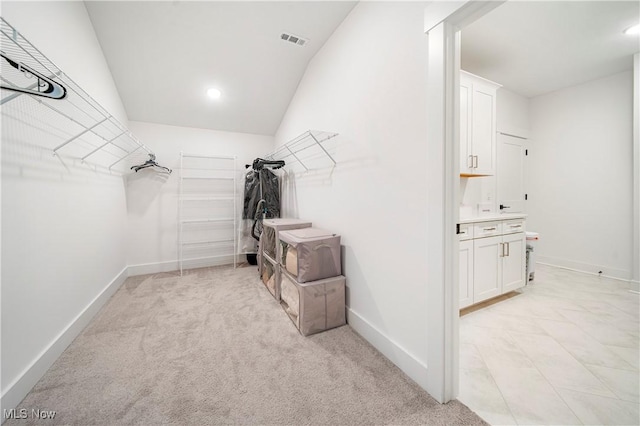 walk in closet with vaulted ceiling and light carpet