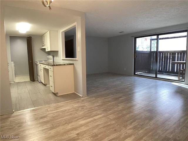 kitchen featuring dark stone countertops, light hardwood / wood-style floors, white cabinets, and range