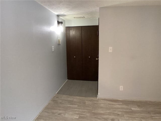 corridor with a textured ceiling and light wood-type flooring