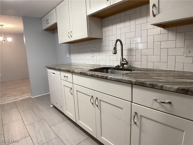 kitchen with white cabinets, dishwasher, sink, and dark stone countertops