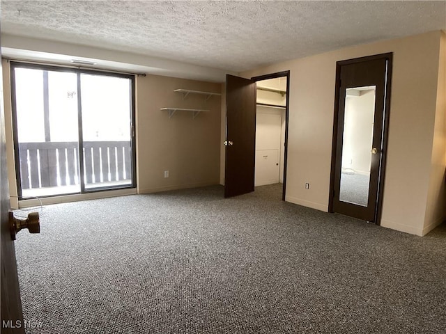 unfurnished bedroom featuring carpet flooring, a textured ceiling, and a spacious closet