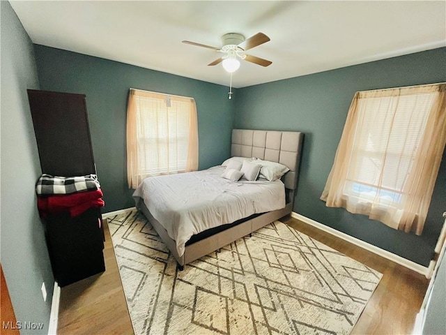 bedroom featuring multiple windows, hardwood / wood-style flooring, and ceiling fan