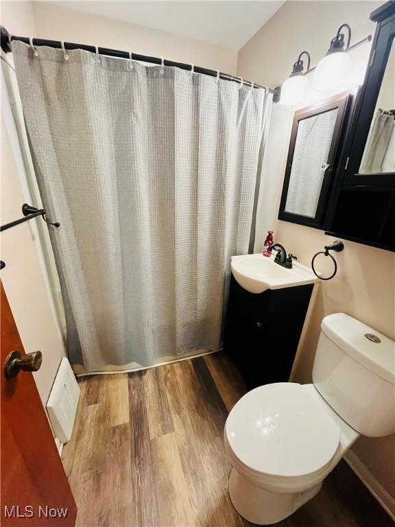 bathroom with a shower with curtain, vanity, hardwood / wood-style floors, and toilet