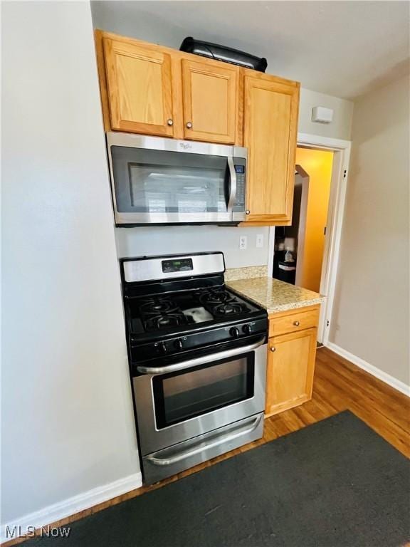 kitchen featuring dark hardwood / wood-style flooring, light brown cabinets, and appliances with stainless steel finishes