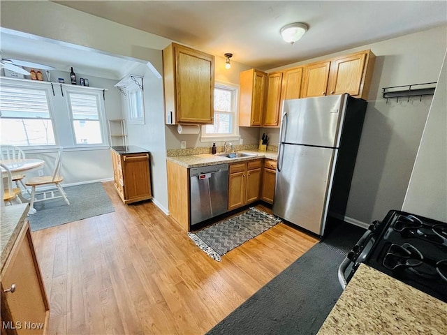 kitchen with stainless steel appliances, sink, and light wood-type flooring