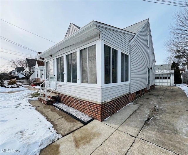 view of snow covered exterior with a garage and an outdoor structure