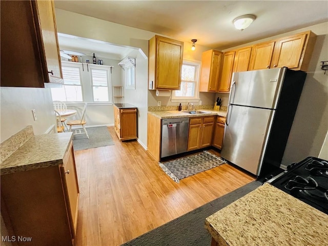 kitchen with sink, stainless steel appliances, and light hardwood / wood-style floors