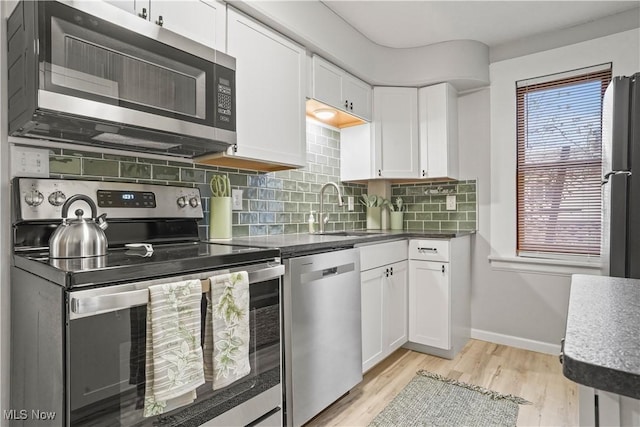 kitchen featuring sink, light hardwood / wood-style flooring, white cabinetry, stainless steel appliances, and tasteful backsplash