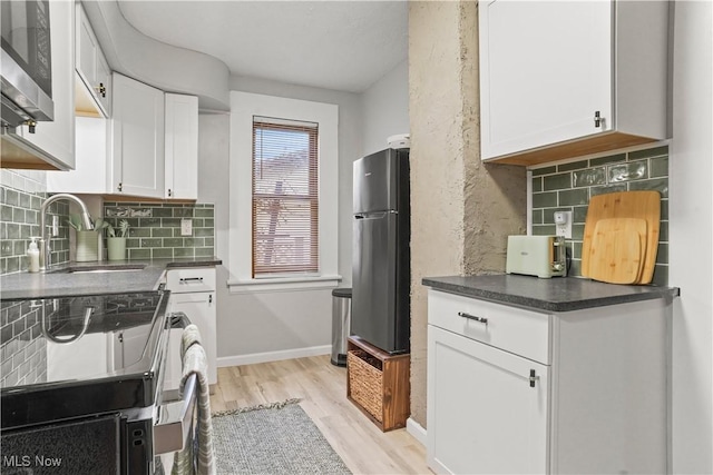 kitchen with appliances with stainless steel finishes, sink, decorative backsplash, and white cabinets