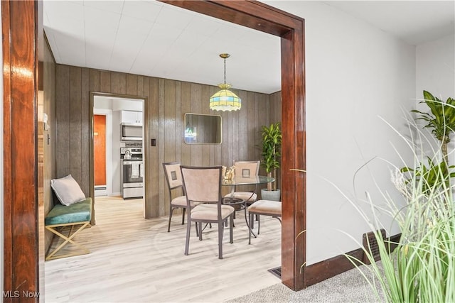 dining room with light wood-type flooring and wooden walls