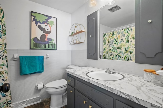 bathroom featuring vanity, tile walls, and toilet