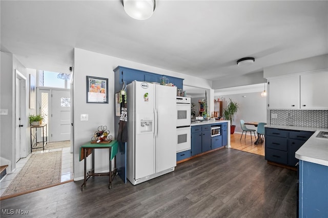 kitchen featuring white appliances, dark wood-type flooring, blue cabinetry, white cabinets, and decorative backsplash