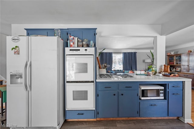 kitchen featuring dark wood-type flooring, appliances with stainless steel finishes, blue cabinets, and kitchen peninsula