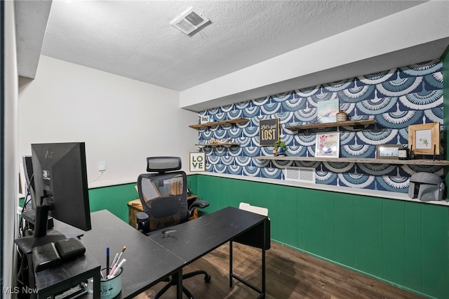 office area with dark hardwood / wood-style floors, wooden walls, and a textured ceiling