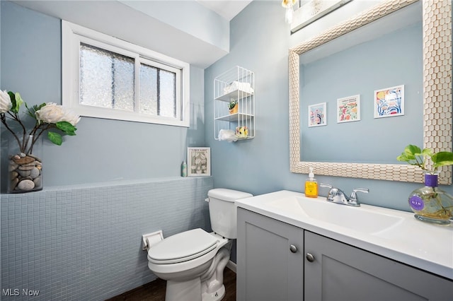 bathroom featuring tile walls, vanity, and toilet