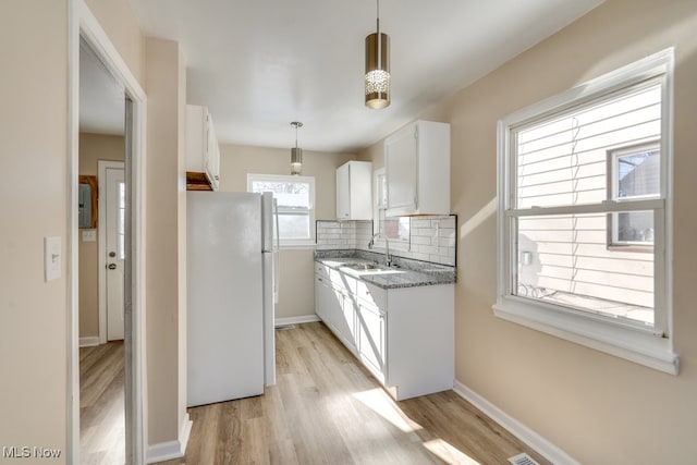 kitchen featuring sink, decorative light fixtures, white refrigerator, white cabinets, and backsplash