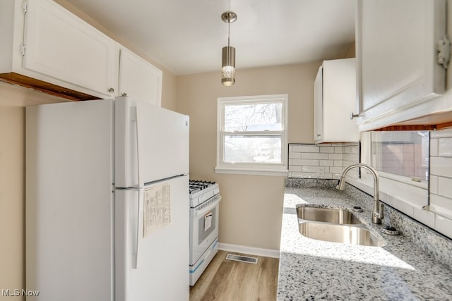 kitchen with decorative light fixtures, sink, white cabinets, light stone counters, and white appliances