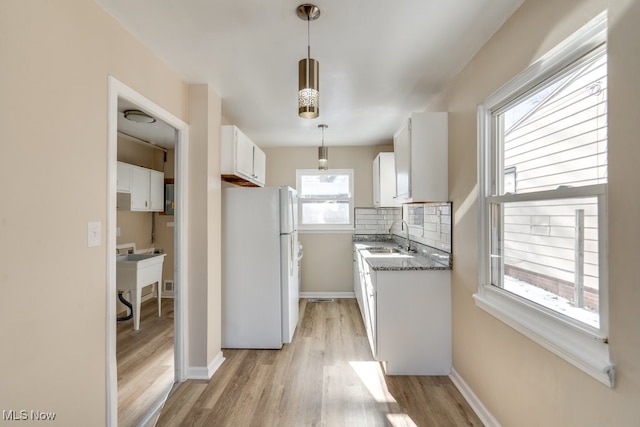 kitchen with sink, white cabinetry, white refrigerator, tasteful backsplash, and decorative light fixtures