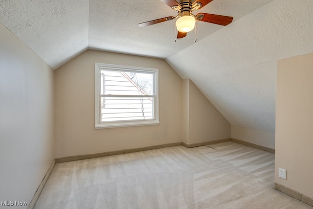 bonus room with lofted ceiling, light carpet, and a textured ceiling