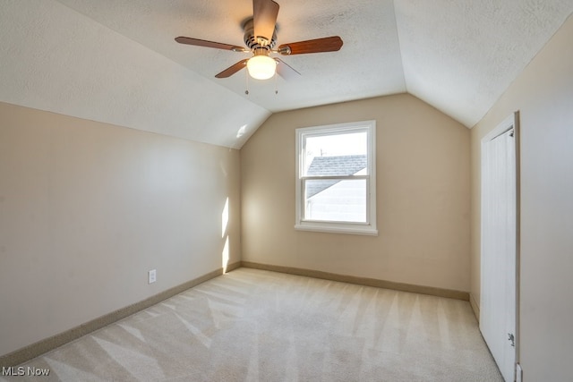 additional living space featuring ceiling fan, lofted ceiling, light carpet, and a textured ceiling