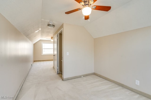 bonus room with ceiling fan, lofted ceiling, light colored carpet, and a textured ceiling