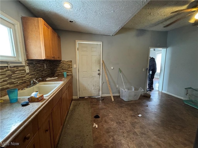 kitchen featuring tasteful backsplash, ceiling fan, sink, and a textured ceiling