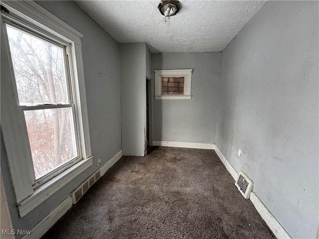 carpeted empty room featuring a textured ceiling