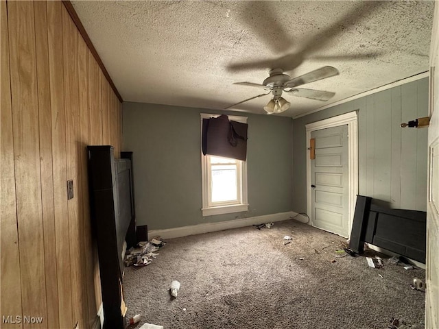 unfurnished bedroom featuring ceiling fan, wooden walls, carpet flooring, and a textured ceiling