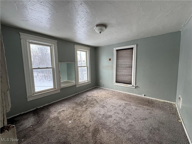 carpeted empty room featuring a textured ceiling