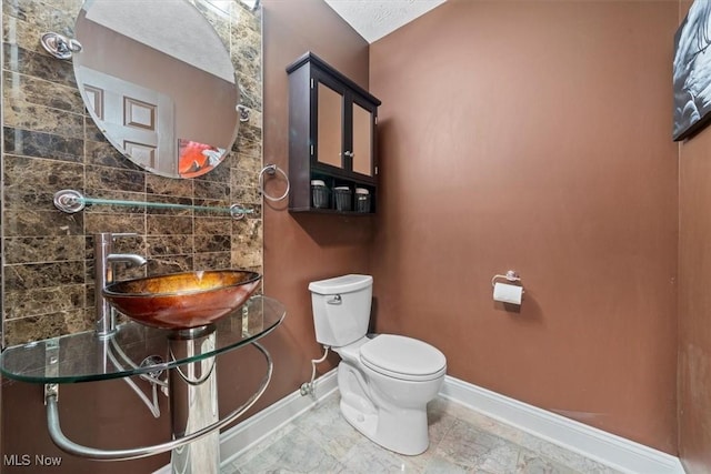 bathroom with sink, backsplash, and toilet