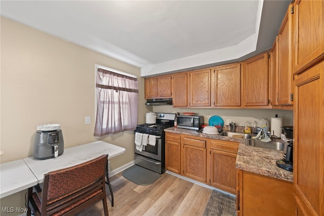 kitchen with stainless steel appliances, light stone counters, and light wood-type flooring