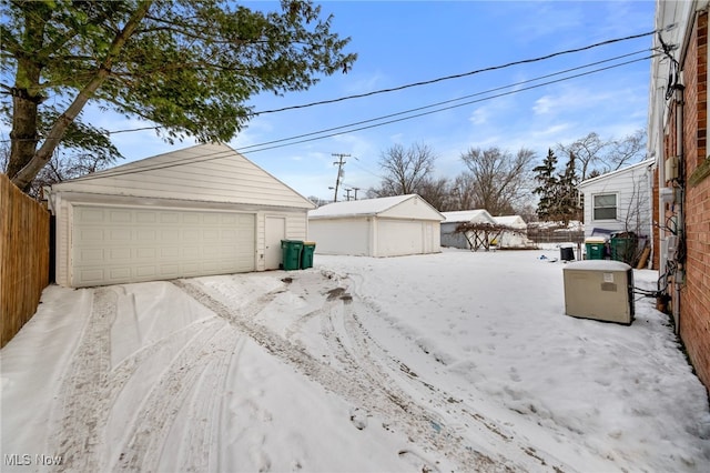 yard covered in snow with a garage and an outbuilding