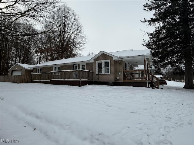 snow covered rear of property featuring a porch and a garage