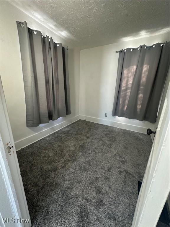 carpeted empty room featuring a textured ceiling