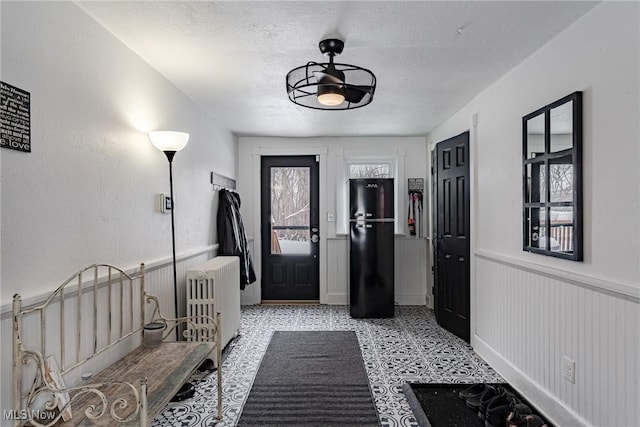 entryway with ceiling fan, radiator heating unit, and a textured ceiling