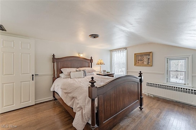 bedroom featuring dark wood-type flooring, radiator heating unit, and vaulted ceiling