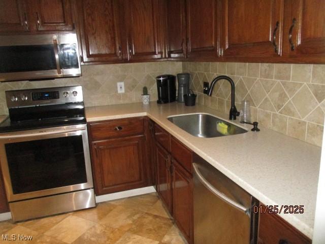 kitchen featuring light tile patterned flooring, appliances with stainless steel finishes, sink, and decorative backsplash