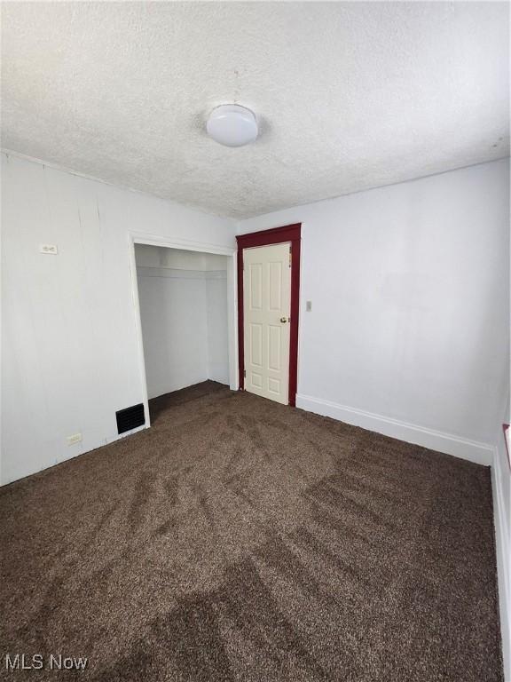 carpeted empty room featuring a textured ceiling