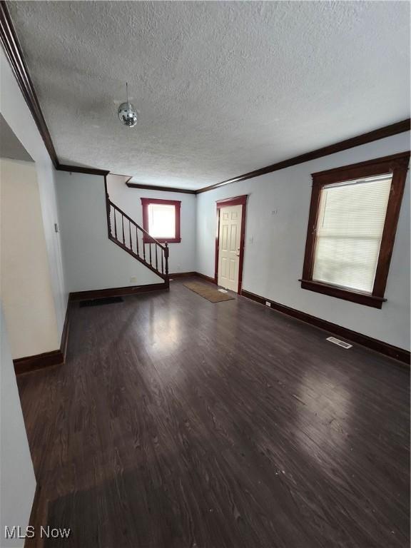 unfurnished room with crown molding, dark hardwood / wood-style floors, and a textured ceiling