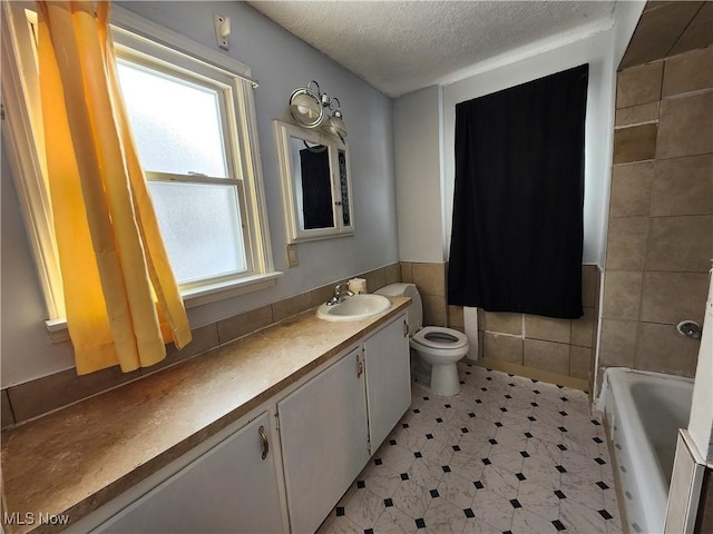 bathroom featuring plenty of natural light, toilet, vanity, and tile walls